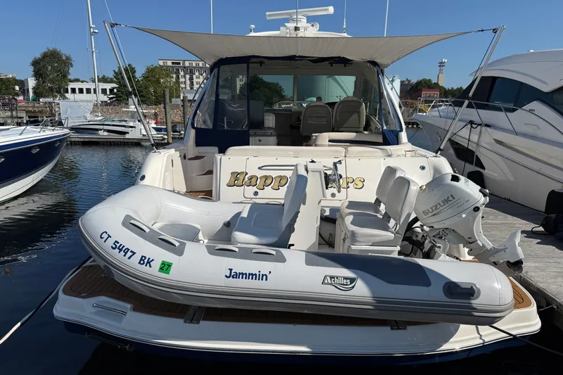 Slide: The Image of 2005 Sea Ray 48 Sundancer yacht docked with inflatable boat, marina background. - 2