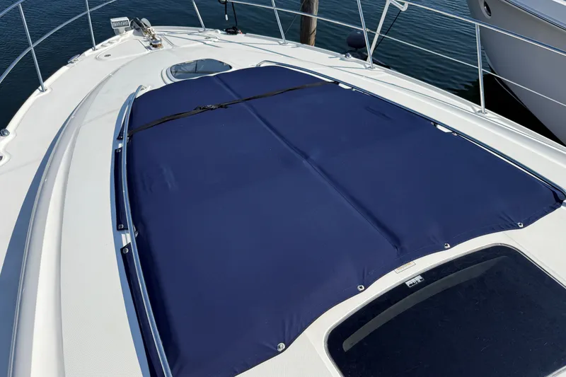 Slide: The Image of 2005 Sea Ray 48 Sundancer yacht deck with blue cover, docked on calm water. - 24