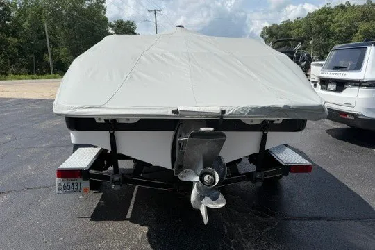 Slide: The Image of 2011 Glastron GT 205 boat with cover, parked on a trailer in a lot. - 32