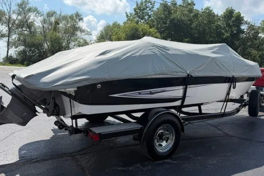 Slide: The Image of 2011 Glastron GT 205 boat covered on trailer, parked outdoors. - 31