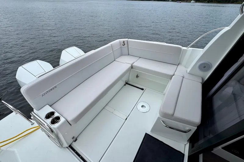 Slide: The Image of 2026 Beneteau Antares 9 boat interior with white seating and cup holders on a calm lake. - 8