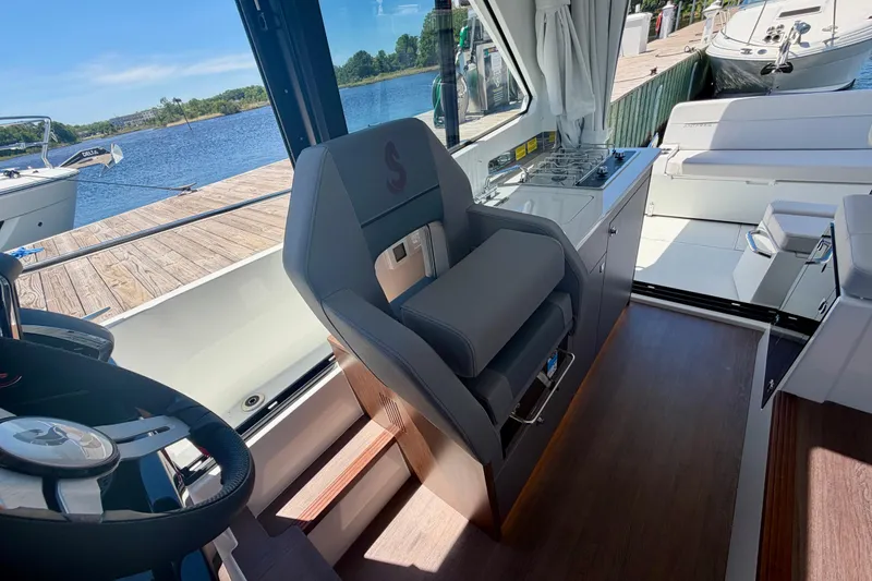 Slide: The Image of Interior of 2026 Beneteau Antares 9 boat, featuring helm seat and kitchenette by the water. - 18