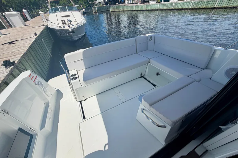 Slide: The Image of 2026 Beneteau Antares 9 boat interior with white seating, docked by the water. - 24