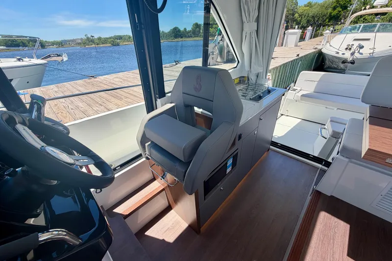Slide: The Image of Interior of 2026 Beneteau Antares 9 boat, featuring helm and seating area by the water. - 17