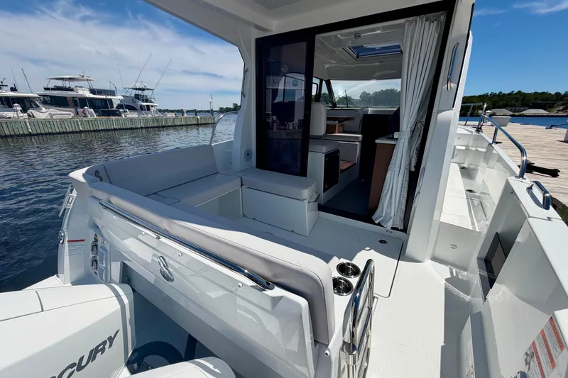 Slide: The Image of 2026 Beneteau Antares 9 boat interior, featuring seating and open cabin at a marina. - 23