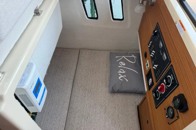 Slide: The Image of 2024 Ranger Tugs R-27 cabin interior with control panel and "Relax" pillow. - 51