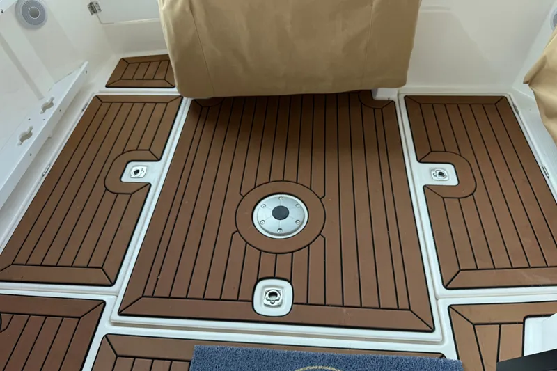 Slide: The Image of 2024 Ranger Tugs R-27 boat deck with brown wood-like flooring and covered seating. - 5