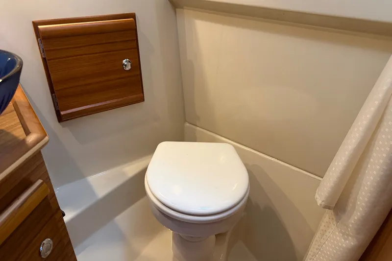Slide: The Image of 2024 Ranger Tugs R-27 boat bathroom with wooden cabinet and white toilet. - 45