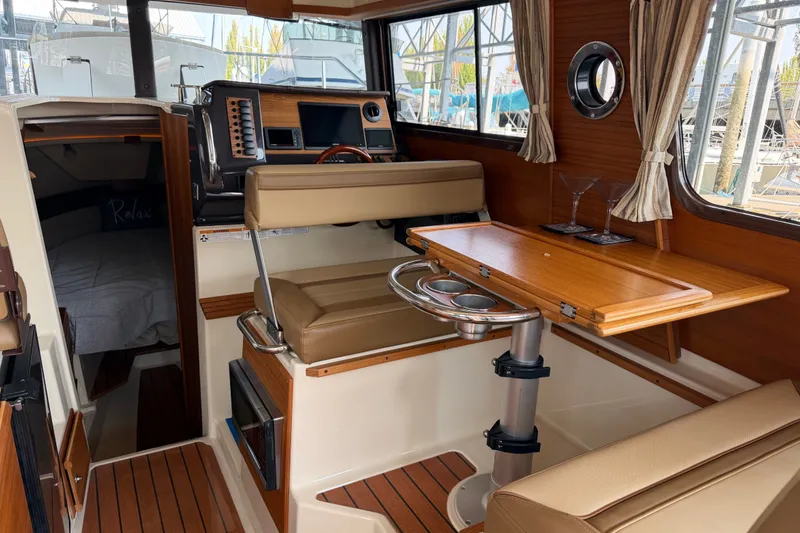 Slide: The Image of Interior of 2024 Ranger Tugs R-27, featuring a cozy cabin with wood accents and seating. - 21