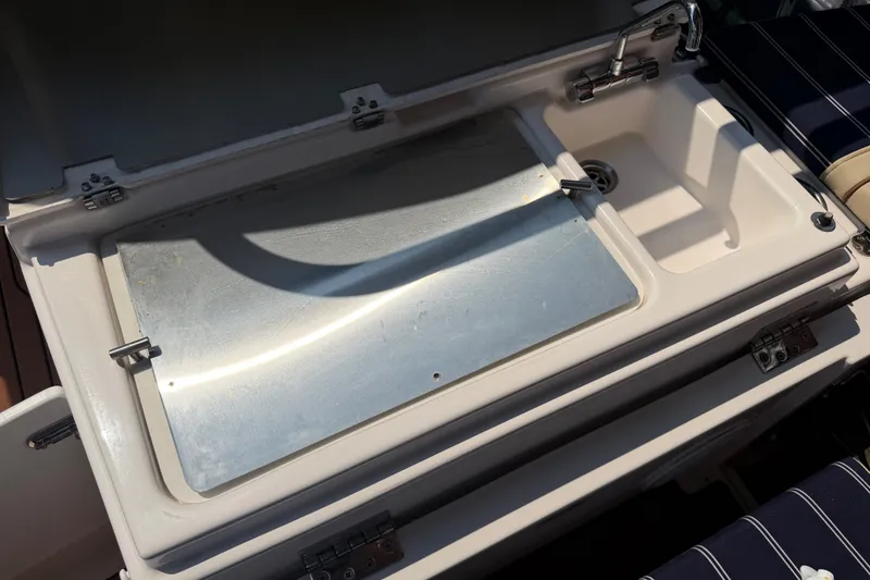 Slide: The Image of 2024 Ranger Tugs R-27 boat sink and storage compartment, featuring a sleek metal cover. - 8