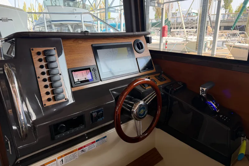 Slide: The Image of 2024 Ranger Tugs R-27 helm with modern controls and navigation display at marina. - 25