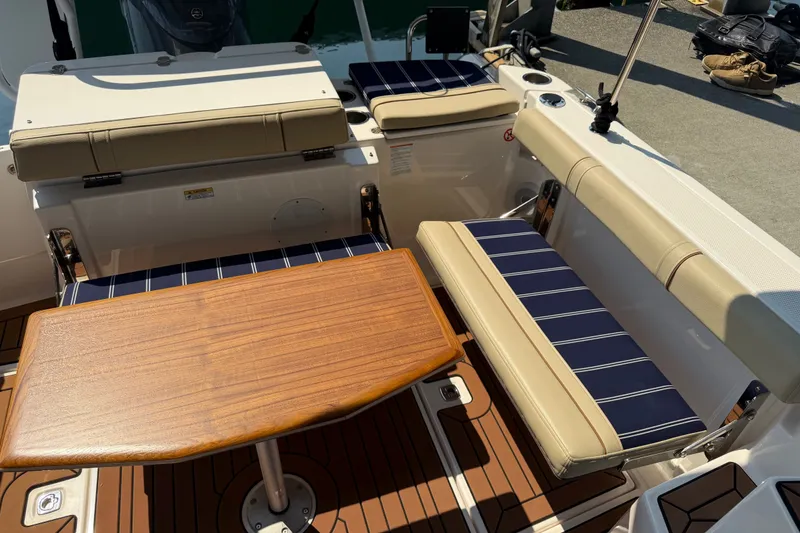 Slide: The Image of 2024 Ranger Tugs R-27 boat interior with cushioned seating and wooden table. - 3