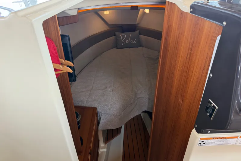 Slide: The Image of 2024 Ranger Tugs R-27 cabin interior with cozy bed and wooden accents. - 40