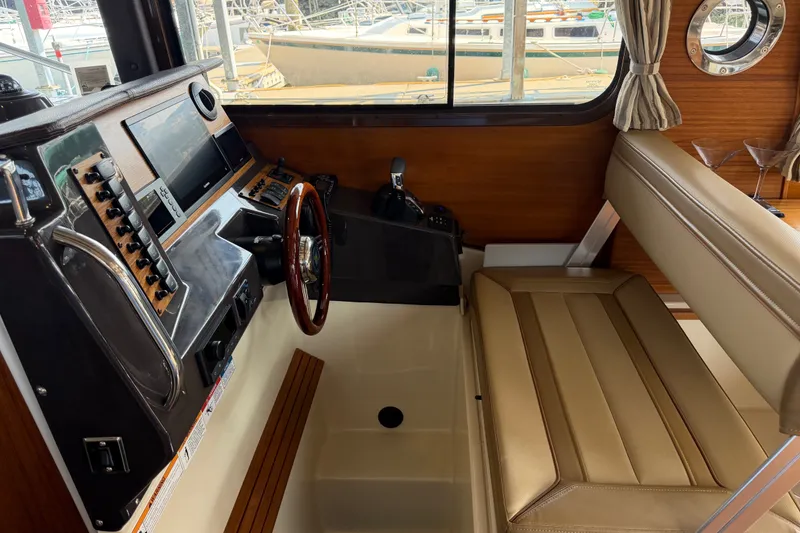 Slide: The Image of 2024 Ranger Tugs R-27 helm with modern controls, wood accents, and comfortable seating. - 24