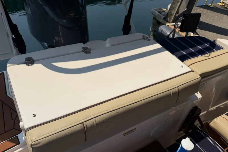 Slide: The Image of 2024 Ranger Tugs R-27 boat deck with cushioned seating and storage compartment. - 7