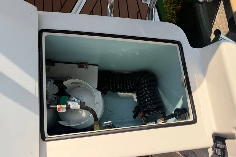 Slide: The Image of Storage compartment on 2024 Ranger Tugs R-27 boat with coiled hose and equipment. - 12