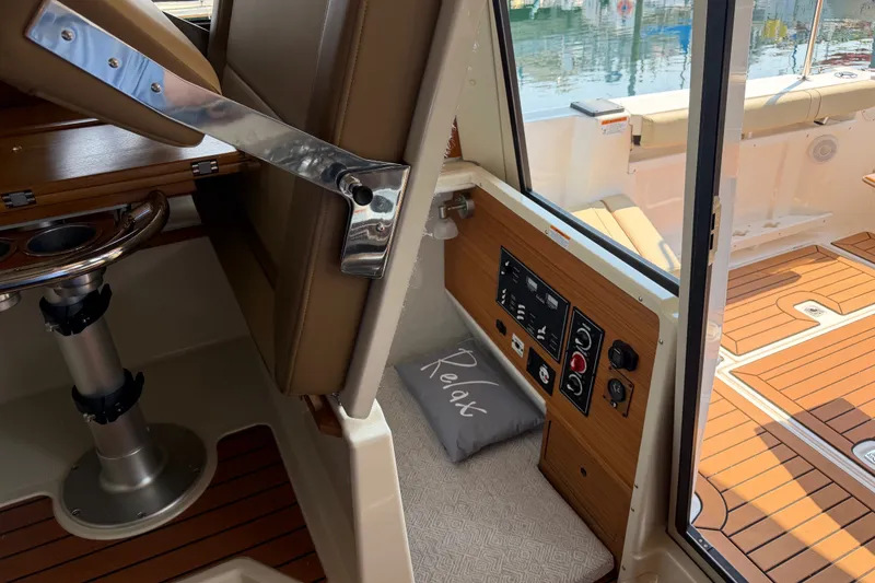 Slide: The Image of 2024 Ranger Tugs R-27 interior with control panel, seating, and "Relax" pillow. - 49