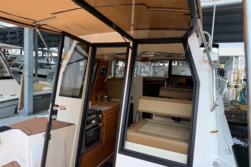 Slide: The Image of 2024 Ranger Tugs R-27 interior view with seating and kitchenette at marina. - 19