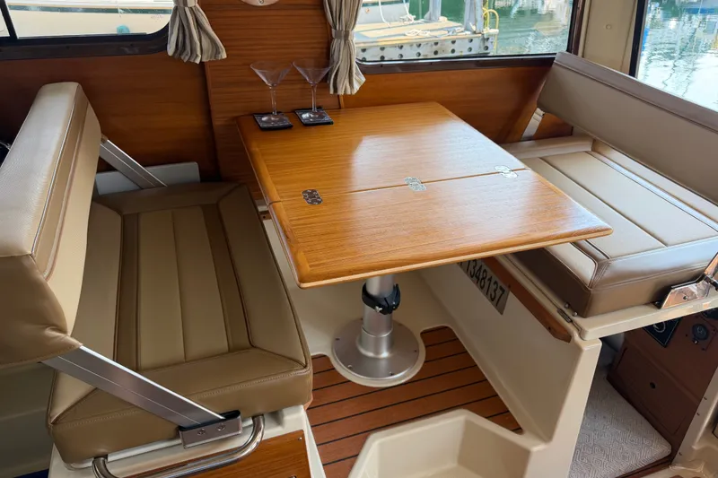 Slide: The Image of Interior of 2024 Ranger Tugs R-27 with wooden table and beige seating. - 38