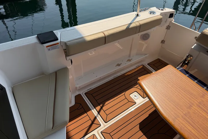 Slide: The Image of 2024 Ranger Tugs R-27 boat interior with teak flooring and cushioned seating. - 5