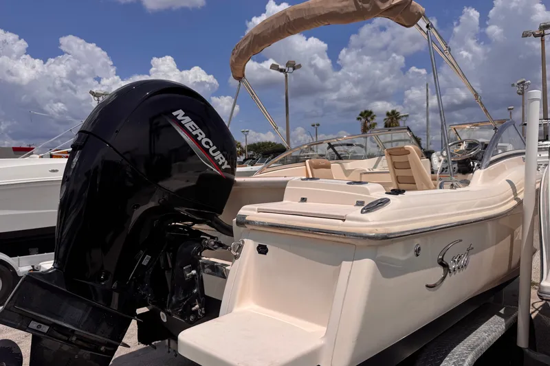 Slide: The Image of 2023 Scout 210 Dorado boat with Mercury engine, parked under a cloudy sky. - 3