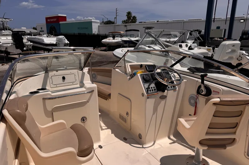 Slide: The Image of 2023 Scout 210 Dorado boat interior with steering wheel and seating at a marina. - 7