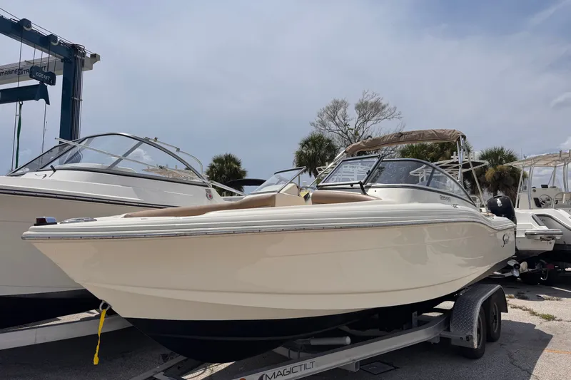 The Image of 2023 Scout 210 Dorado boat on trailer, displayed outdoors under a clear sky. - 1