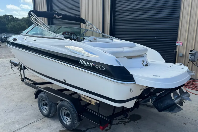 Slide: The Image of 2007 Kayot Z 220 boat on trailer, white with black accents, parked outside a building. - 2