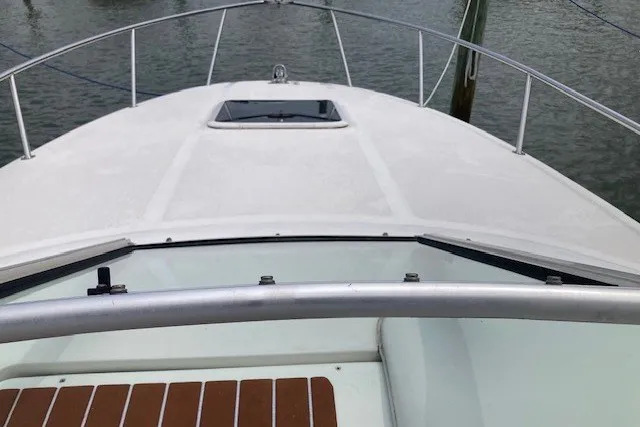 Slide: The Image of 2002 Sea Ray Sundancer 260 boat deck with railing and hatch, docked on calm water. - 16