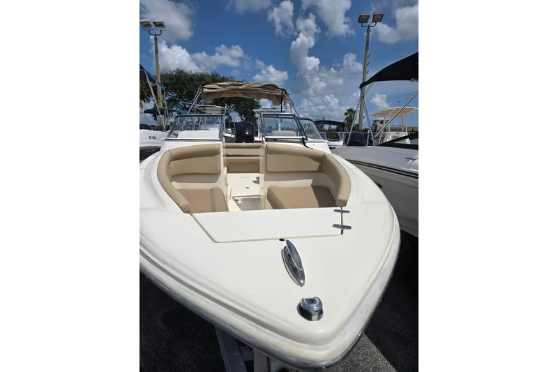 Slide: The Image of 2022 Scout 210 Dorado boat with beige seating, docked under a blue sky. - 3