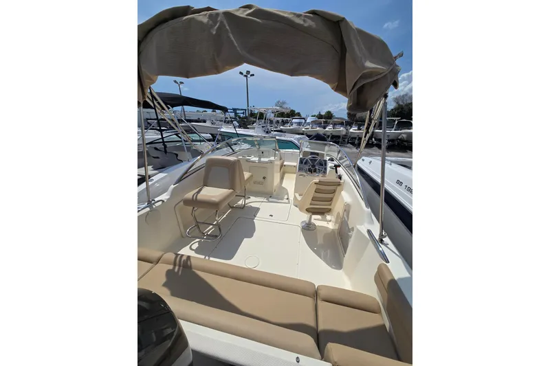 Slide: The Image of 2022 Scout 210 Dorado boat interior with seating and canopy under clear sky. - 10
