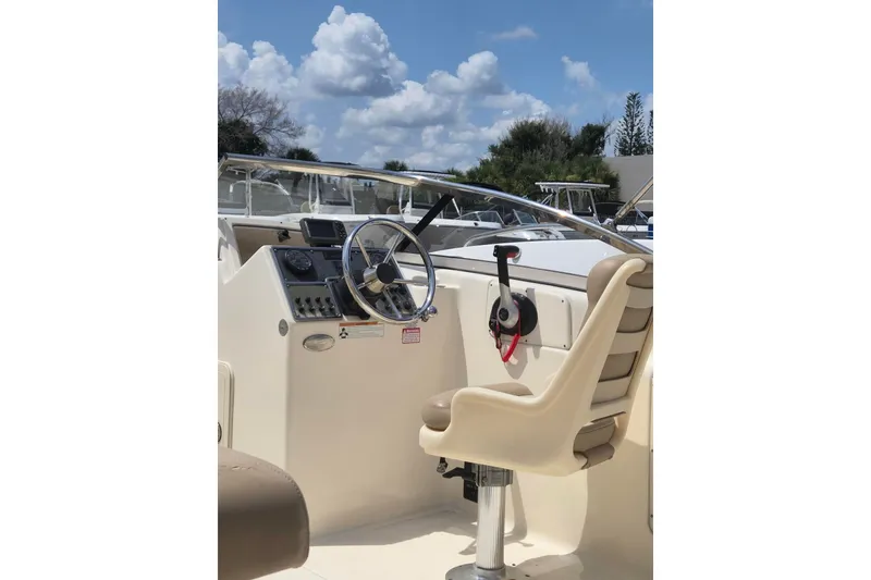 Slide: The Image of 2022 Scout 210 Dorado boat cockpit with steering wheel and captain's chair under blue sky. - 8