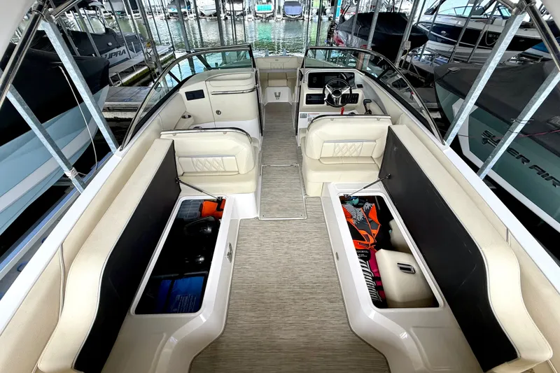 Slide: The Image of 2019 Regal LS6 boat interior with open storage compartments, beige seating, and steering console. - 34