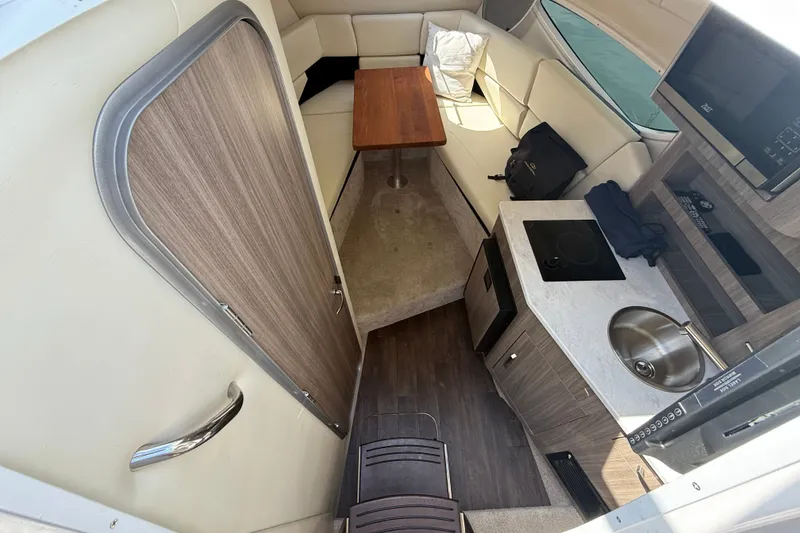 Slide: The Image of Interior of 2023 Regal 26 XO boat featuring kitchenette, seating, and wooden accents. - 25