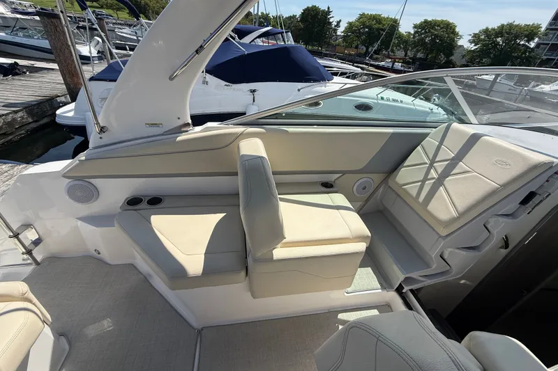 Slide: The Image of 2023 Regal 26 XO boat interior with beige seating and cup holders at a marina. - 13