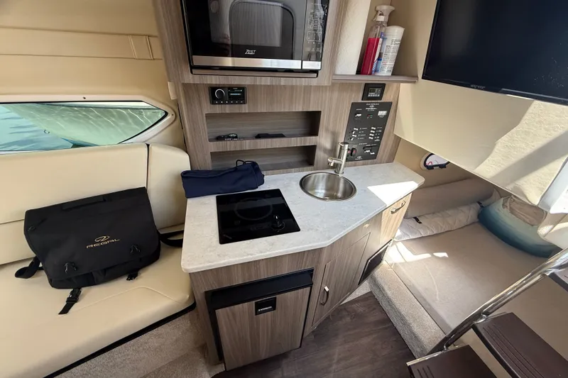 Slide: The Image of 2023 Regal 26 XO boat interior with kitchenette, sink, and seating area. - 30
