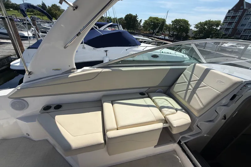 Slide: The Image of 2023 Regal 26 XO boat interior with beige seating and cup holders at a marina. - 14