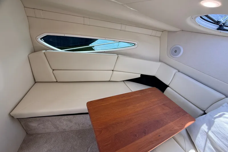 Slide: The Image of 2023 Regal 26 XO cabin interior with beige seating and wooden table. - 28