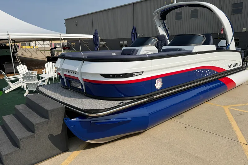 Slide: The Image of 2027 Sylvan G5 LZ DC pontoon boat with patriotic design, displayed outdoors. - 3