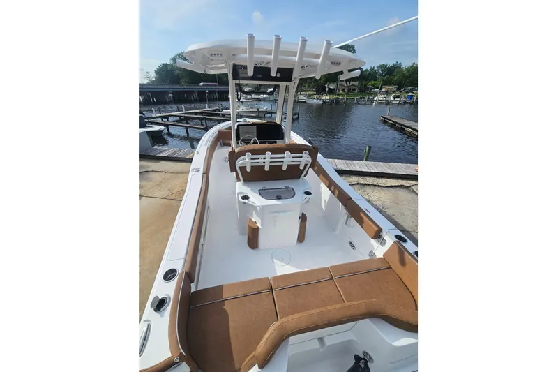 Slide: The Image of 2027 Sea Hunt Ultra 239 SE boat with brown seating, docked by a serene waterfront. - 10