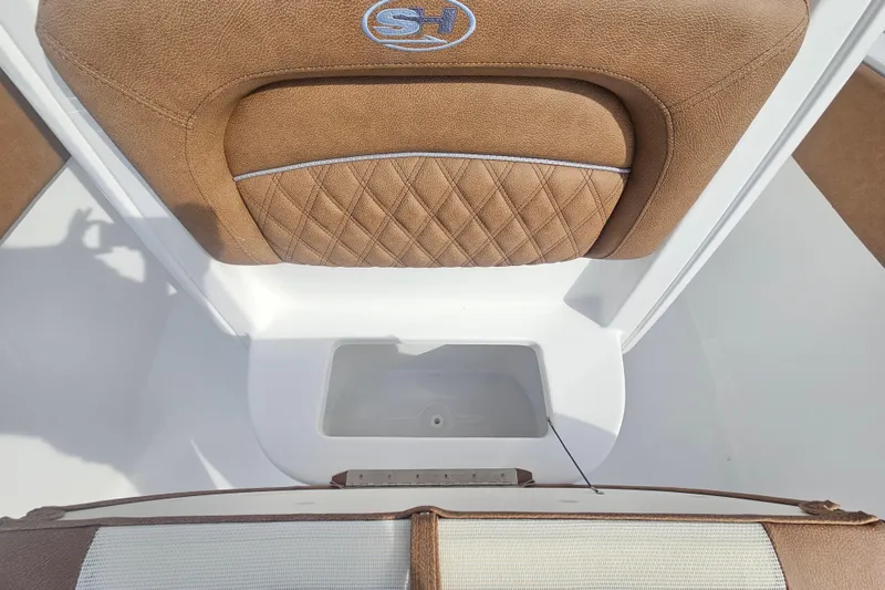 Slide: The Image of 2027 Sea Hunt Ultra 239 SE boat interior with tan cushioned seating and storage compartment. - 27
