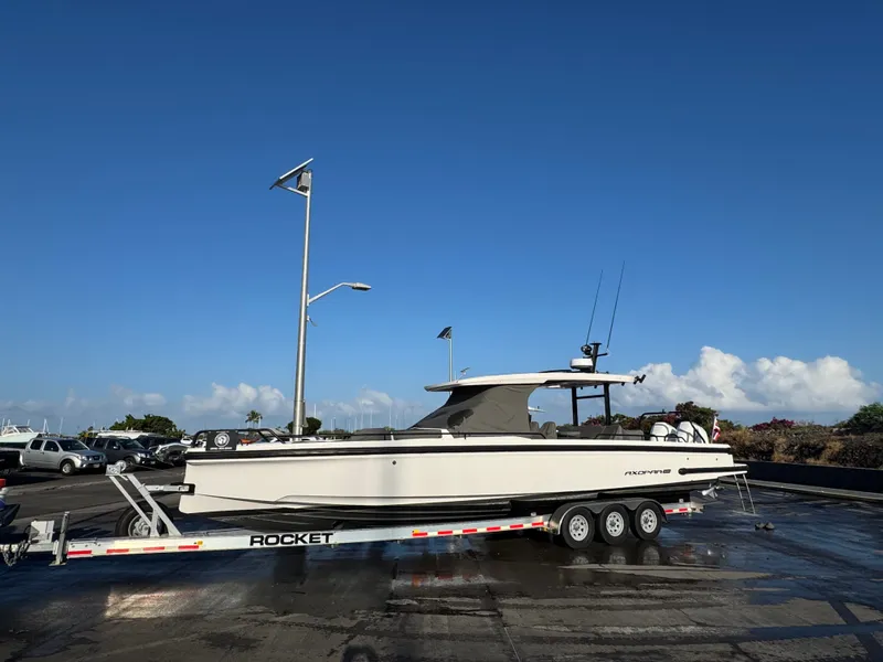 Slide: The Image of A 2021 Axopar 37 Sun-Top boat on a trailer, parked on a wet parking lot. - 11