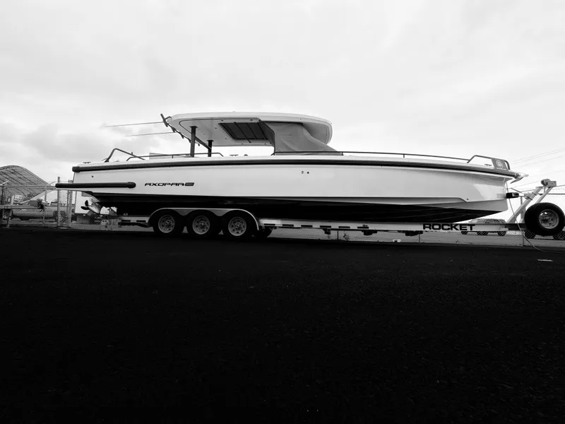 Slide: The Image of A 2021 Axopar 37 Sun-Top boat is on a trailer in a parking area. - 2