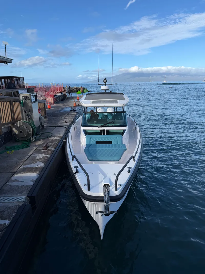 Slide: The Image of A 2021 Axopar 37 Sun-Top docked. The sky is clear and the water is calm. - 10