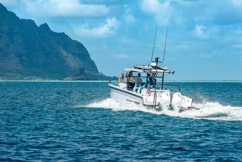 Slide: The Image of A 2021 Axopar Brabus 37 Sun-Top boat cruising on open water with mountains in the background. - 5