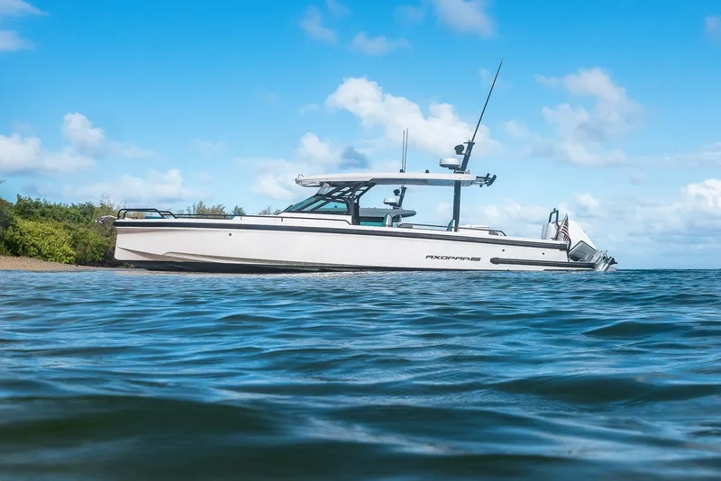 The Image of A 2021 Axopar Brabus 37 Sun-Top boat sits in calm water near a shoreline. - 0