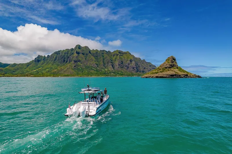 Slide: The Image of An Axopar Brabus 37 Sun-Top boat cruises on turquoise waters with a mountainous island backdrop. - 4