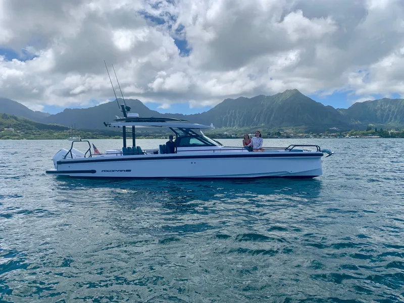 Slide: The Image of A 2021 Axopar Brabus 37 Sun-Top on calm water with a mountainous backdrop. - 8