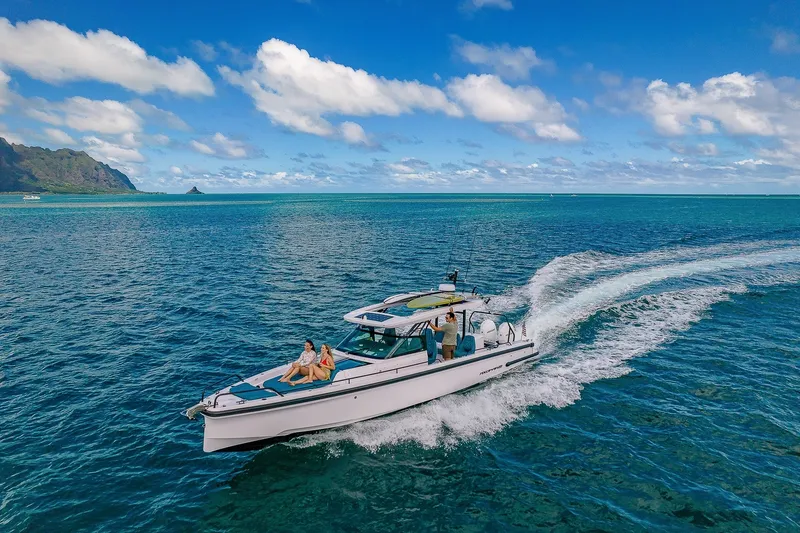 Slide: The Image of A 2021 Axopar Brabus 37 Sun-Top speeds across the blue sea, with mountains in the background. - 2