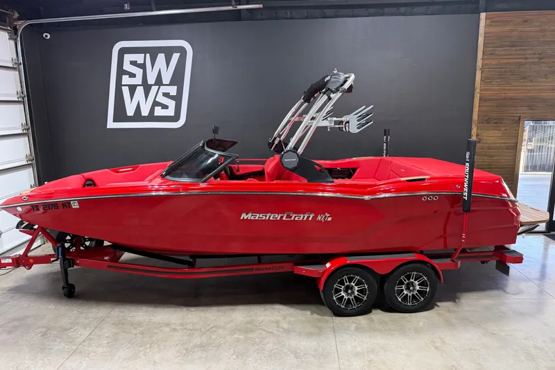 The Image of 2023 MasterCraft NXT24 red boat on trailer in showroom. - 0